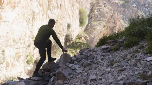 Silhouette of a Hiker Man Climbing Onto a Rocky Hill A Man Hiking Up a Huge Mountain Field of Rock