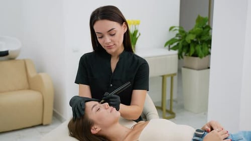 Woman Applies Eyebrow Makeup to Another Woman