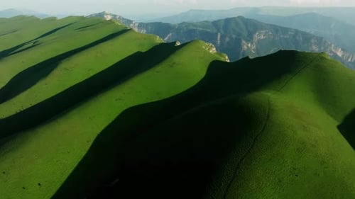 A Rugged Highland Landscape with Rolling Green Hills Cascading Into Vast Grasslands Under a Vibrant