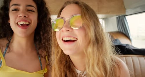 Two Young Women Blow Bubbles in a Van