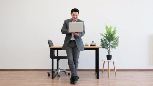 Confident Businessman Using Laptop in Modern Office Setting