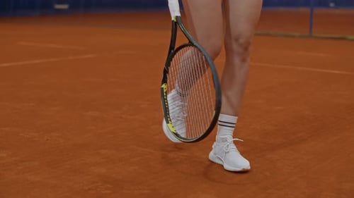 Woman in Sneakers Lifting Tennis Ball with Racket on Clay Court
