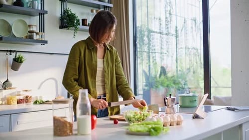 Woman cuts fresh vegetables on kitchen counter