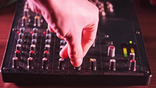 Sound Engineer Move Faders Level on Audio Mixer Console in Neon Light CloseUp