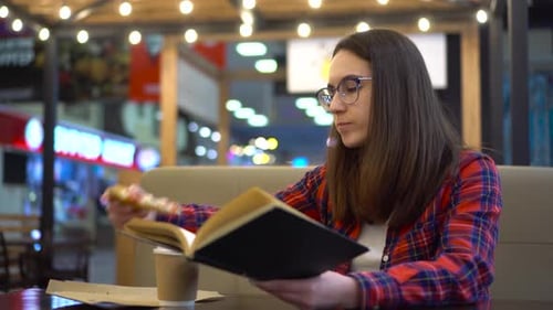 A Young Woman is Reading a Book in a Cozy Cafe