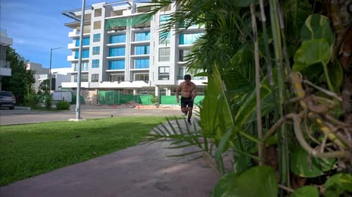 Man Running Shirtless in Suburban Park