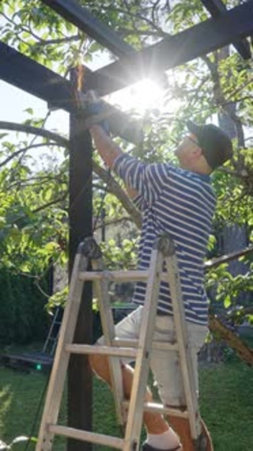 Hombre usando una amoladora angular para cortar un soporte de metal en una pérgola de madera