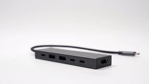 A black USB-C hub with multiple ports spins on a white surface.