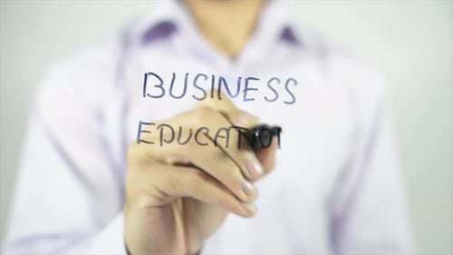 Hand Writes Business Education on Clear Surface