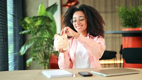 Cheerful Woman Successfully Saving Money in a Piggy Bank for Financial Future