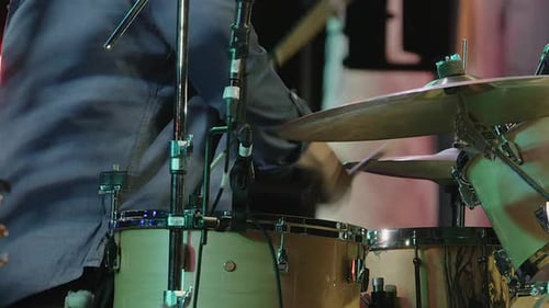 Drummer plays drum set on stage during public concert performance