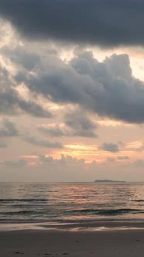 Time lapse vertical video of dramatic sunrise with orange sky at the ocean in a cloudy day.