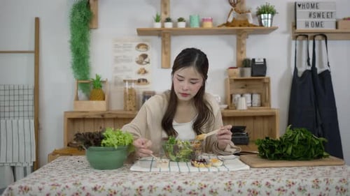 Young Woman Enjoying Salad at Kitchen Table