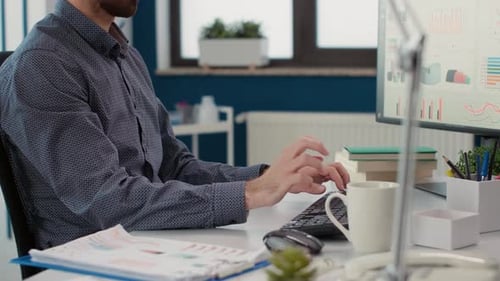 Man Typing on Keyboard While Drinking From Mug