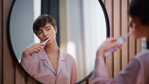 Modelo alegre cepillándose la boca, espejo de baño, mujer, limpiándose los dientes