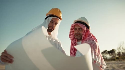 Two Construction Engineers Reviewing Blueprints on Site