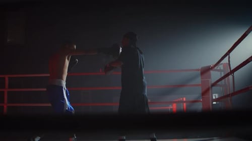 Boxer Training with Coach in Dark Boxing Ring