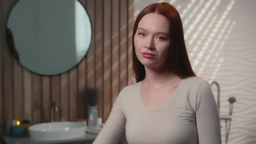 Femme mécontente sérieuse, fille, femme rousse, dans la salle de bain de la maison, mécontente, montrant le pouce vers le bas