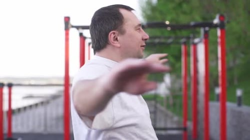 Man stretching arms at outdoor workout facility