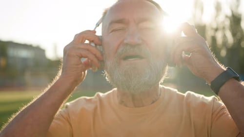 Senior Man Puts on Wireless Headphones Smiling