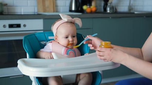 Cute Infant Being Fed in High Chair