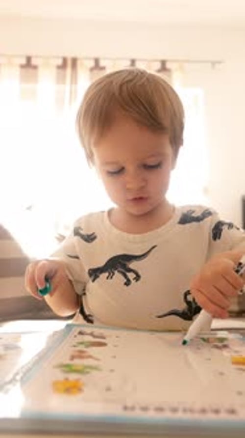 Boy Draws with Markers on a Book