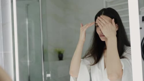 Woman Applying Facial Massage in Bright Bathroom