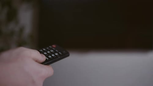 Un hombre ve la televisión y usa un control remoto El hombre controla la televisión con control remoto, fondo borroso