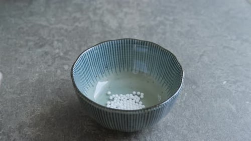 Pouring homeopathic pills out of a glass jar into a small bowl