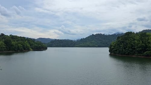 Lake and green mountain natural scenery in Malaysia. A large river bank with island trees and cloud