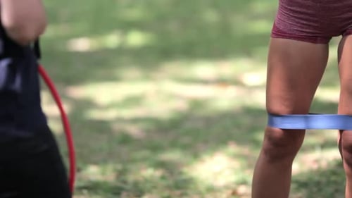 Woman Exercising with Band Outdoors in Sunny Park