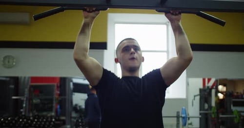 Athlete Man Pulling Up on Crossbar in Gym Fitness Club