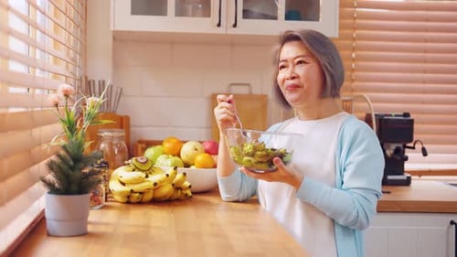 Senior Woman Eating Salad at Kitchen Counter