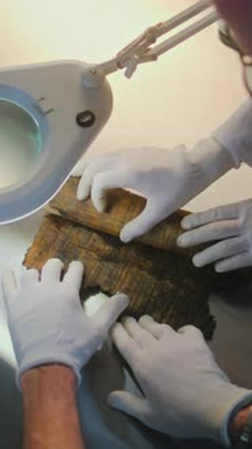 Unrolling fragile scroll under lamp in laboratory