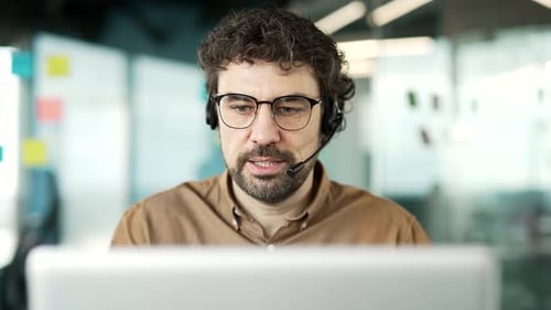 Corporate operator who works in customer support speaks on a video call using a laptop. Call center