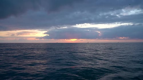 The sun is setting over the ocean, casting a warm glow on the water