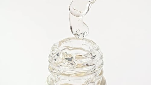 Clear Serum Dropping into Glass Cosmetic Bottle