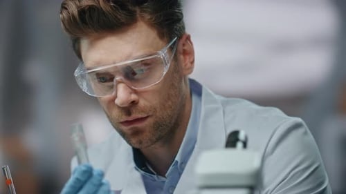 Scientist Using Microscope and Holding Test Tube in Lab