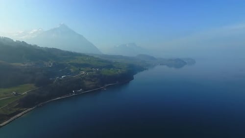 Aerial View of the Snow Rocky Cliffs with Forest By the Lake