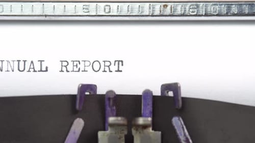 Annual Report phrase close up being typing and centered on a sheet of paper on old vintage type