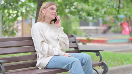 Woman Talking on Phone While Sitting on Bench