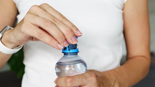 Woman Closes Cap on Water Bottle, Close Up