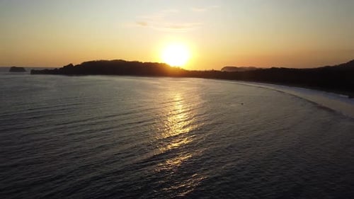 Golden sunset over calm ocean with silhouetted coastline