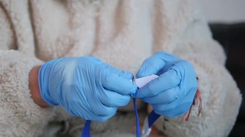 Close-up of medical staff unbuckling a snap tourniquet band.