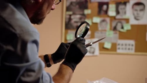 Closeup Detective's Office Middleaged Investigator in Shirt and Tie Sitting Desk Examining Evidence