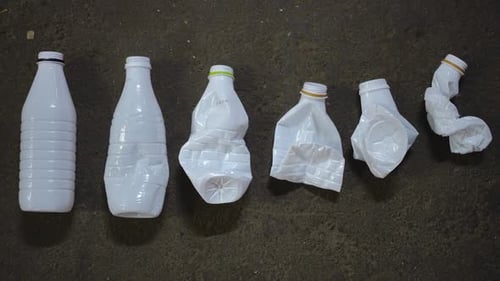 Row of White Plastic Bottles From Whole to Smashed Top View Closeup Used Material for Sorting and