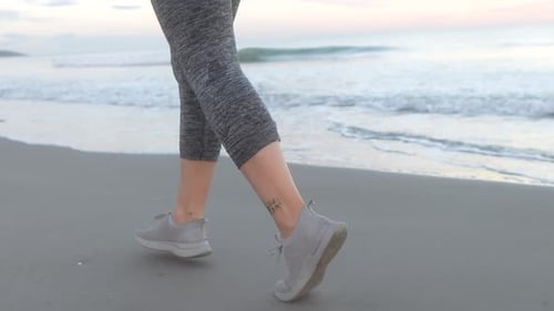 Frauenfüße laufen am Strand entlang