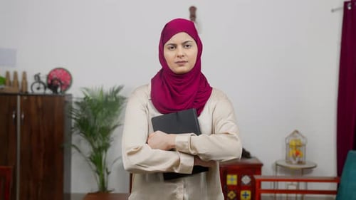 Selbstbewusste muslimische Frau im Hijab-Schal liest Buch und schaut in die Kamera