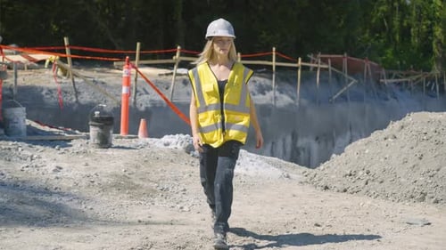 Woman Wearing Hardhat Walks at Construction Site