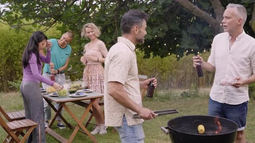 Cheerful Mature Men Toast with Beer Having Barbecue for Multiracial Women Standing at Table Garden